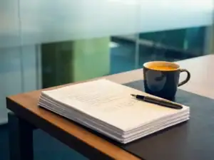 Arbeidscontract op modern bureau met pen en kop koffie in zacht noordelijk kantoorlicht.